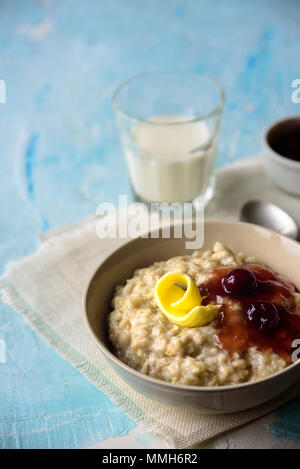 Gruau porrige avec beurre et confiture de cerise sur le tableau bleu. Avec le verre de lait. Le petit-déjeuner Banque D'Images