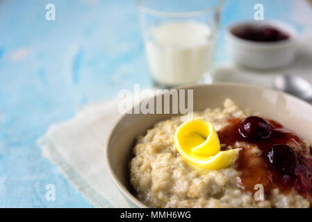 Gruau porrige avec beurre et confiture de cerise sur le tableau bleu. Avec le verre de lait. Le petit-déjeuner Banque D'Images