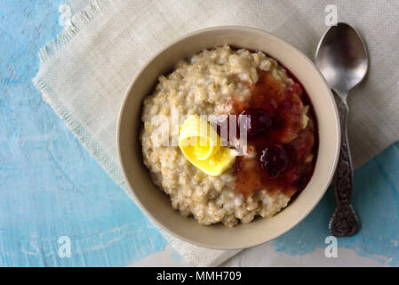 Gruau porrige avec beurre et confiture de cerise sur le tableau bleu. Avec le verre de lait. Le petit-déjeuner Banque D'Images