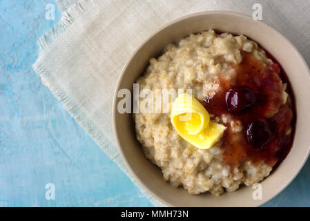 Gruau porrige avec beurre et confiture de cerise sur le tableau bleu. Avec le verre de lait. Le petit-déjeuner Banque D'Images
