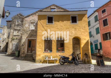 Le centre de l'Istrie, Croatie, avril 2018 - Scooter garé en face d'une vieille maison jaune à l'angle de deux rues dans la vieille ville de Buzet Banque D'Images