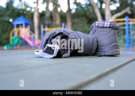 Retiré enfant paire de bottes et chaussettes avec les enfants jouant sur les promenades en parc en banlieue australienne. Banque D'Images