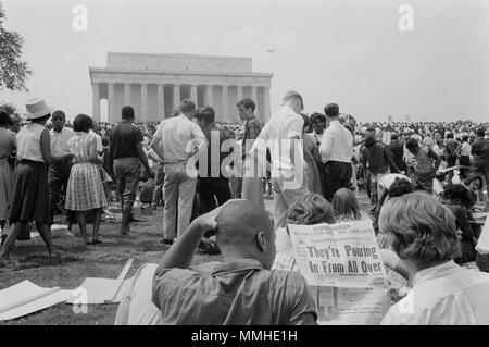 La photographie montre une foule d'Américains africains et blancs sur le terrain du Mémorial de Lincoln ; deux hommes en premier plan lire un journal avec le titre : 'ils affluent de partout." Banque D'Images