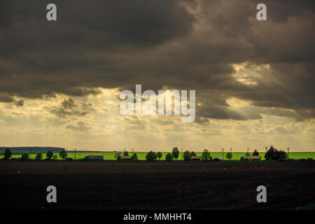 Coucher du soleil avec des nuages au domaine agricole et de la route avec des voitures et camions Banque D'Images