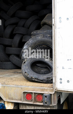 La bande de roulement des pneus usés utilisés vieux vieux pneus de différentes tailles et voies des voitures et des camions sont stockés à l'intérieur un vieux semi-remorque avec une porte ouverte pour pr Banque D'Images