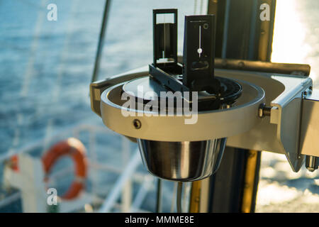Close up of marine nautique compas magnétique sur le bateau ou en bateau avec beau coucher de soleil sur l'arrière-plan. Calcul de l'erreur de la boussole en tenant compte de la ligue Banque D'Images