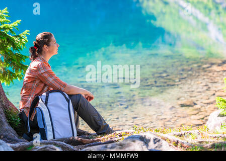 Voyageur avec un sac à dos est assis au bord du lac Morskie Oko dans les Tatras et admire Banque D'Images