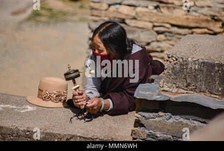 Pèlerin tibétain fait tourner un moulin à prières à l'extérieur de la Sainte Ecriture Imprimerie Bakong monastère à Dege, Sichuan, Chine Banque D'Images