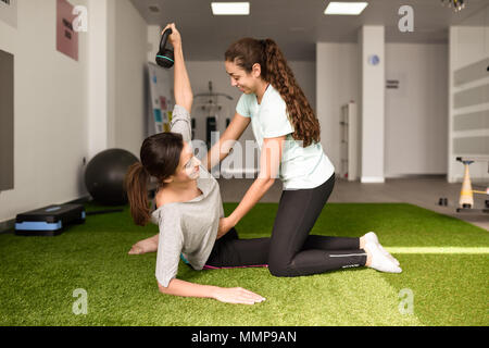 Thérapeute physique aide les jeunes caucasian woman avec exercice avec haltère au cours de la réadaptation dans le gymnase de l'hôpital. Physiothérapeute femelle tr Banque D'Images