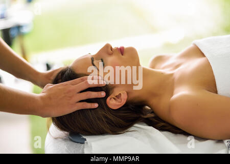 Young caucasian woman recevant un massage de la tête dans un centre de spa avec les yeux fermés. Patiente est sous traitement par des therapi Banque D'Images