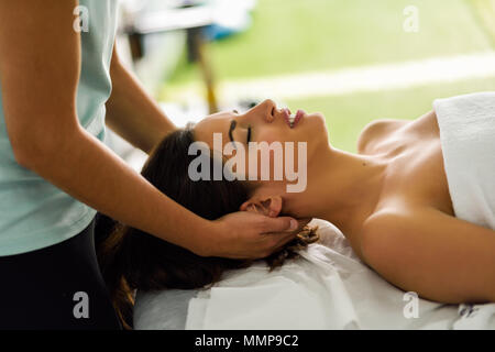 Young caucasian woman recevant un massage de la tête dans un centre de spa avec les yeux fermés. Patiente est sous traitement par des therapi Banque D'Images