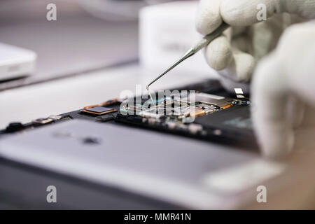 Travailler avec un microscope. Dispositif de micro-électronique. Close-up mains d'un travailleur de service réparation smartphone moderne. Service de réparation et de concept. Banque D'Images
