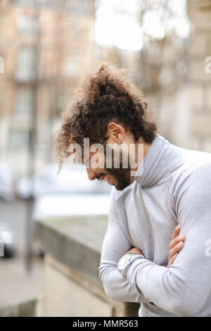 La moitié african man wearing pullover à col roulé gris et ayant les cheveux bruns bouclés. Banque D'Images