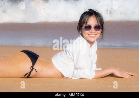 Jeune femme en chemise blanche et costume de bain sur le sable au Palm Beach Sydney, Australie Banque D'Images