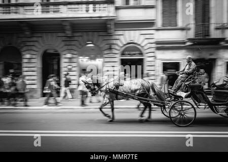 Un chariot tiré par un cheval le long de la Via del Corso à Rome en noir et blanc Banque D'Images