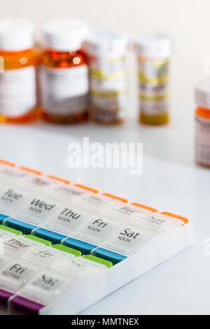 Organisateur pour un régime quotidien de prescriptions de médicaments avec des bouteilles de pilules dans l'arrière-plan Banque D'Images