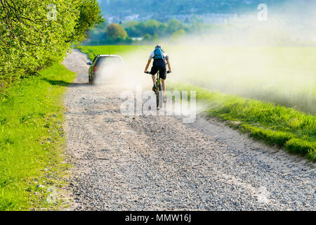 Un cycliste, équitation, une route poussiéreuse derrière une voiture dans un nuage de poussière. Randonnée à vélo en vacances en République tchèque. Banque D'Images