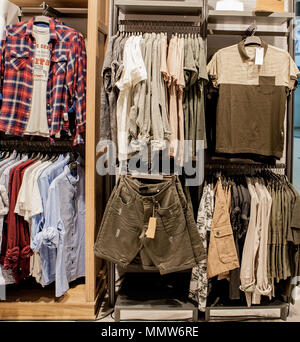 Shorts, chemises, T-shirts et une veste sur l'étagère du magasin. Des vêtements à la mode sur les étagères du magasin. Vitrine, vente, shopping. Luxe et fashionab Banque D'Images