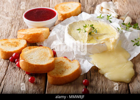 Cuisine traditionnelle française Camembert avec l'ail, le thym est servi avec du pain grillé et sauce aux baies close-up sur la table horizontale. Banque D'Images