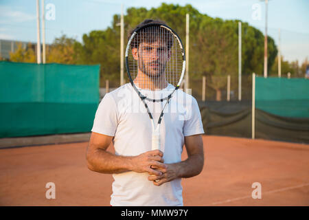 Portrait artistique de jeune joueur de tennis avec raquette de tennis en face du visage. Banque D'Images