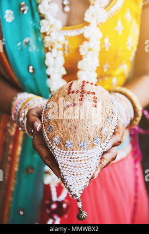 Indiwn la main avec la mariée (mehndi henna) avec des tas de bracelets bangles ou sur son poignet et maintenant le coconut shagun nariyal l'élément pour la prière cerem Banque D'Images