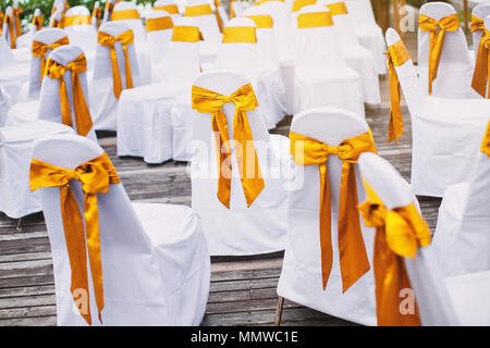 Les chaises spandex blanc aléatoire avec couvercle ceinture organza or en attente de décoration de mariage de plage arrangement Banque D'Images