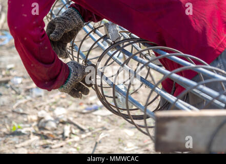 Les mains des travailleurs mettez des gants à l'aide de la main pour fil de fer pour attacher la structure de la maison ou du bâtiment. Banque D'Images