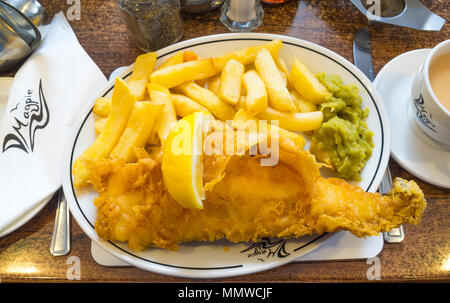 Excellent poisson et frites au célèbre café Magpie à Whitby petits pois purée d'aiglefin servi avec une tranche de citron et d'une tasse de thé Banque D'Images