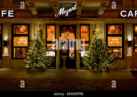 Windows illuminé de Café Mozart au moment de Noël en soirée avec des arbres de Noël et les gens qui passent par Banque D'Images