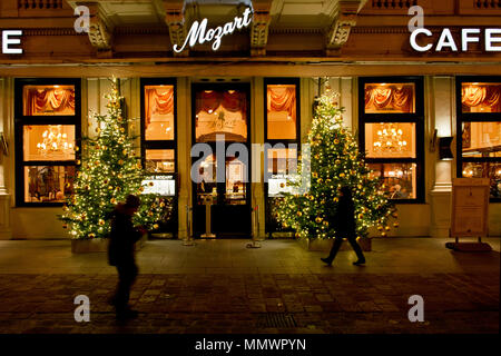 Windows illuminé de Café Mozart au moment de Noël en soirée avec des arbres de Noël et les gens qui passent par Banque D'Images