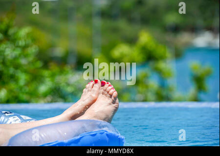 Petites Antilles Antigua îles dans les Caraïbes Antilles - Woman on inflatable dans une piscine à débordement et vue sur English Harbour Banque D'Images