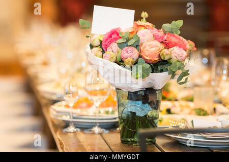 Arrangements, engagements, party concept. sur la longue table en bois servi avec des plats et des verres lumineux il y a un groupe de magnifiques roses en differe Banque D'Images