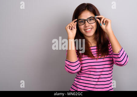 Belle jeune femme indienne portant des lunettes contre bac gris Banque D'Images