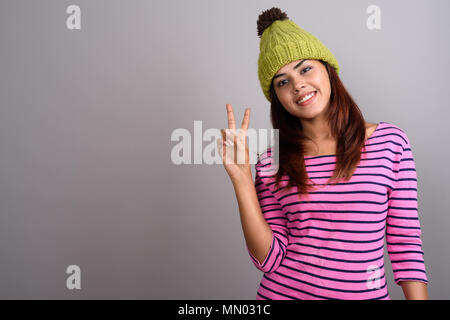 Young beautiful Indian woman wearing hat tricoté gris contre ba Banque D'Images