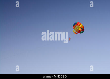 Parachute coloré avec méconnaissable contre ciel bleu à Majorque, Espagne. Banque D'Images