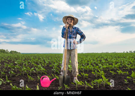 Heureux petit agriculteur avec spade et arrosoir au printemps jardinage champ Banque D'Images