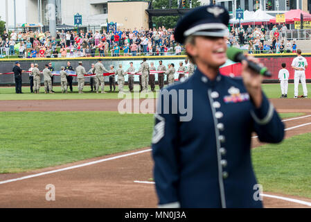 Le sergent-chef. Alyson Jones, Air Force Band de chanteur de vol, chante l'hymne national que les premiers intervenants d'urgence de Wright-Patterson Air Force Base, Ohio, tenir un drapeau géant en champ droit au cours de la Dayton Dragons hommage aux héros à Fifth Third Field au centre-ville de Dayton, le 5 août 2017. La foule a également observé que le colonel McDonald a administré le serment d'engagement personnel à l'enrôlement différé pendant le jeu. (U.S. Air Force photo/ Wesley Farnsworth) Banque D'Images