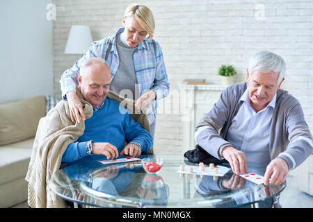 Femme prendre soin de patients âgés qui couvre l'homme tout en jouant à carreaux avec loto avec ami aide à la vie dans la maison. Banque D'Images