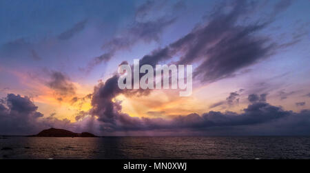 Coucher du soleil avec lightrays chute à travers les nuages dans la plage de corse avec une île à l'avant. Banque D'Images