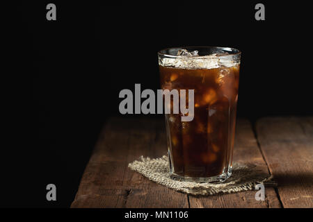 Café de glace dans un grand verre de plus et les grains de café sur une vieille table en bois rustique. Boisson d'été à froid sur un fond sombre avec copie espace Banque D'Images