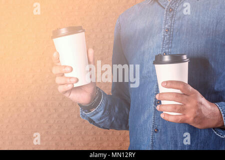 Homme tenant une tasse de café au mur de béton. Banque D'Images