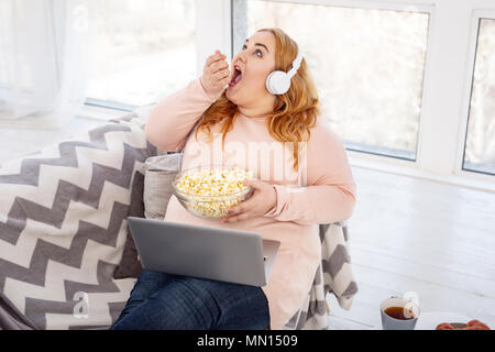 Grosse femme alerte manger beaucoup de popcorn Banque D'Images