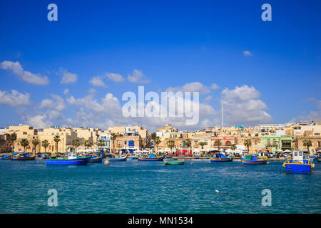 Marsaxlokk port historique plein de bateaux dans Malte. Ciel bleu avec quelques nuages blancs et le village historique. Destination pour les vacances, se détendre et de la pêche Banque D'Images