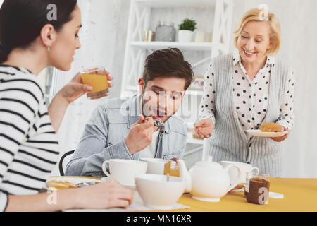 Femme d'âge joyeux servant le petit-déjeuner à son fils Banque D'Images