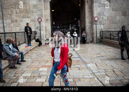 Jérusalem, Israël. 13 mai, 2018. Une femme palestinienne porte une fleur distribué par militants israéliens lors des célébrations marquant le 51e anniversaire de la réunification de Jérusalem, connu sous le nom de la Journée de Jérusalem, à la Porte de Damas à Jérusalem, 13 mai 2018. La Journée de Jérusalem est une maison de vacances israélienne commémorant la création du contrôle israélien sur la vieille ville de Jérusalem après la guerre des Six Jours de 1967. Photo : Ilia Efimovitch/dpa dpa : Crédit photo alliance/Alamy Live News Banque D'Images