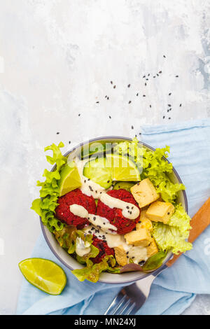 Bol bouddha végétalien boulettes de betterave, légumes, sauce tahini et cuit le tofu. La nourriture végétalienne saine concept. Banque D'Images