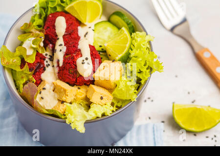 Bol bouddha végétalien boulettes de betterave, légumes, sauce tahini et cuit le tofu. La nourriture végétalienne saine concept. Banque D'Images