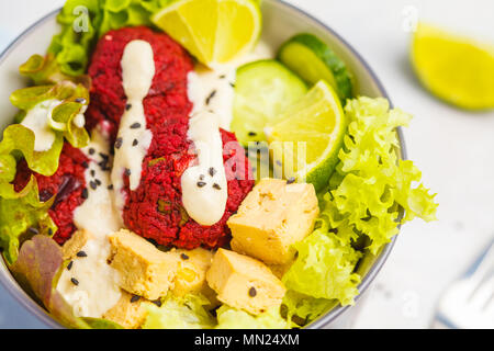 Bol bouddha végétalien boulettes de betterave, légumes, sauce tahini et cuit le tofu. La nourriture végétalienne saine concept. Banque D'Images