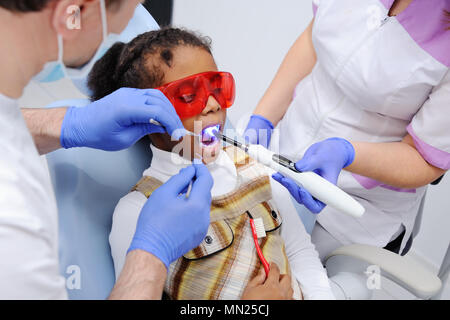 Une petite fille à la peau sombre dans le fauteuil du dentiste Banque D'Images