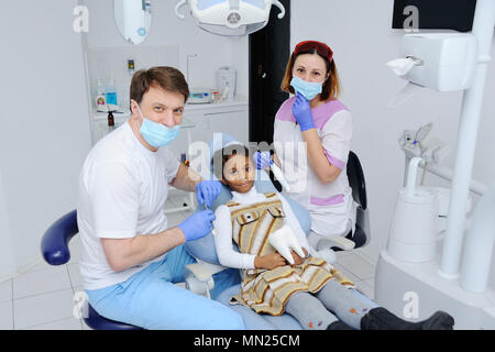 Une petite fille à la peau sombre dans le fauteuil du dentiste Banque D'Images